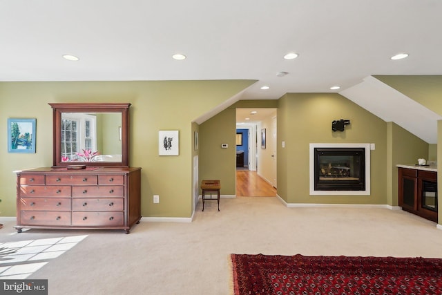 bedroom with recessed lighting, baseboards, light colored carpet, and a glass covered fireplace