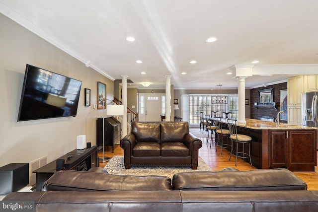 living area featuring stairs, ornamental molding, recessed lighting, wood finished floors, and ornate columns