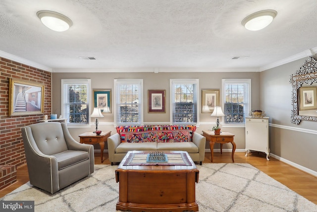 living area with visible vents, a textured ceiling, crown molding, and wood finished floors