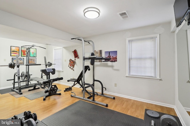 workout area with visible vents, baseboards, and wood finished floors