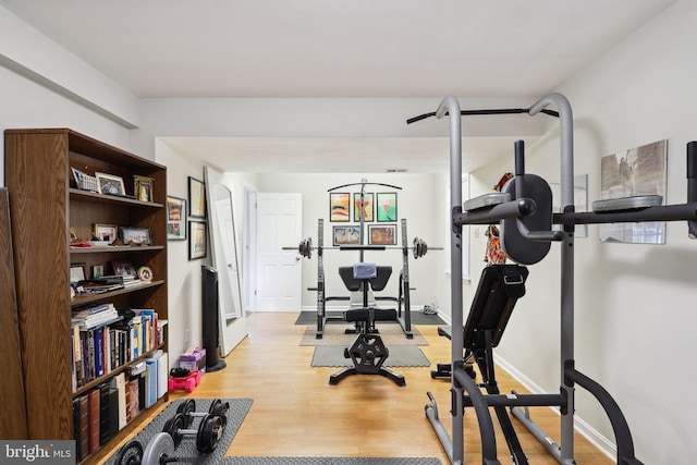 exercise area with light wood-style flooring and baseboards