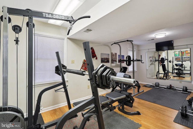 exercise room with visible vents, baseboards, and wood finished floors