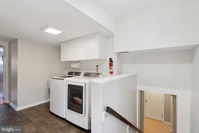 clothes washing area with baseboards, cabinet space, and washer and clothes dryer