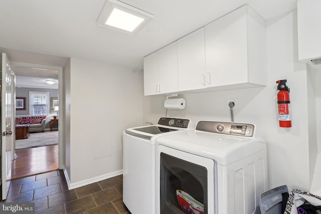 laundry room featuring baseboards, cabinet space, independent washer and dryer, and stone tile flooring