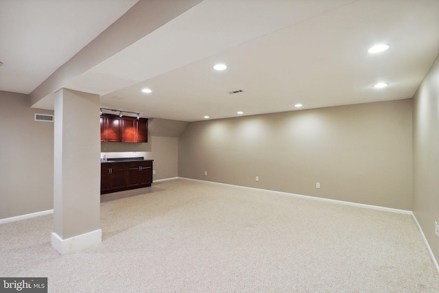 finished basement with visible vents, light carpet, recessed lighting, wet bar, and baseboards