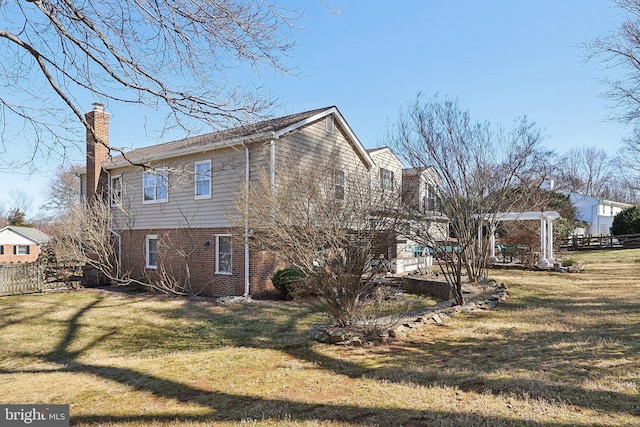 view of home's exterior with a yard, fence, a pergola, and a chimney