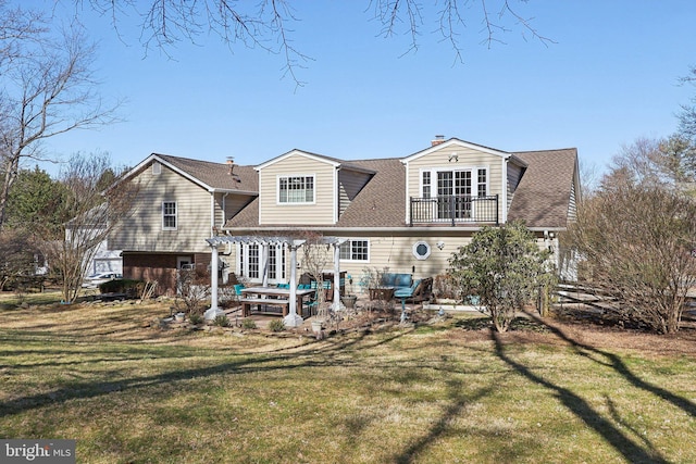 back of house featuring a yard, a balcony, roof with shingles, and a patio area