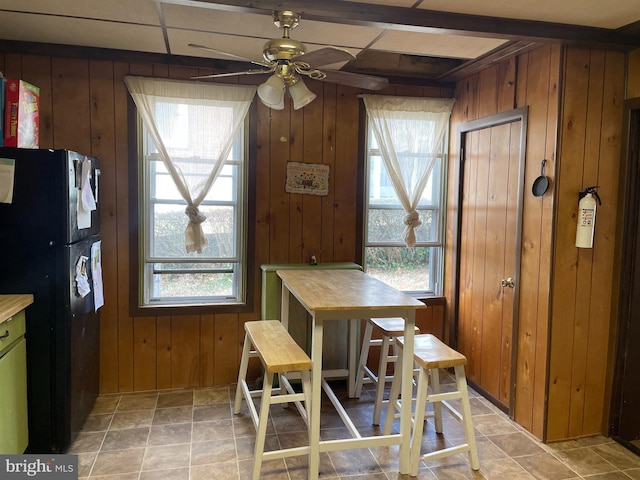 dining space with wood walls and ceiling fan