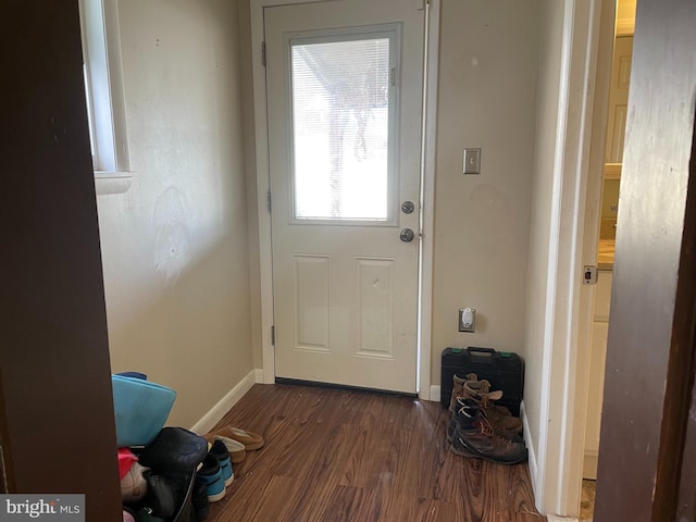 doorway to outside featuring dark wood-style flooring and baseboards