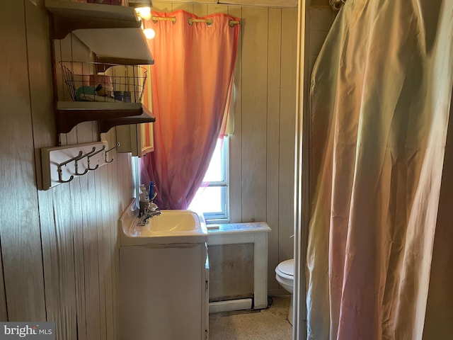 bathroom with wood walls, vanity, toilet, and a shower with curtain