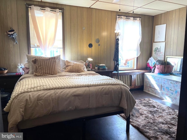 bedroom featuring radiator and wood walls