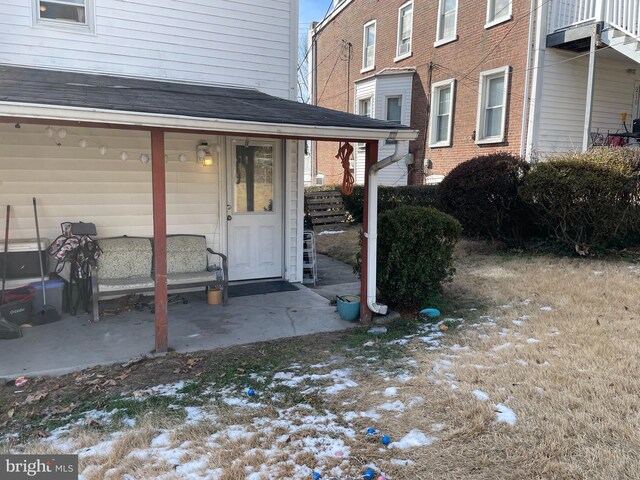 doorway to property featuring roof with shingles