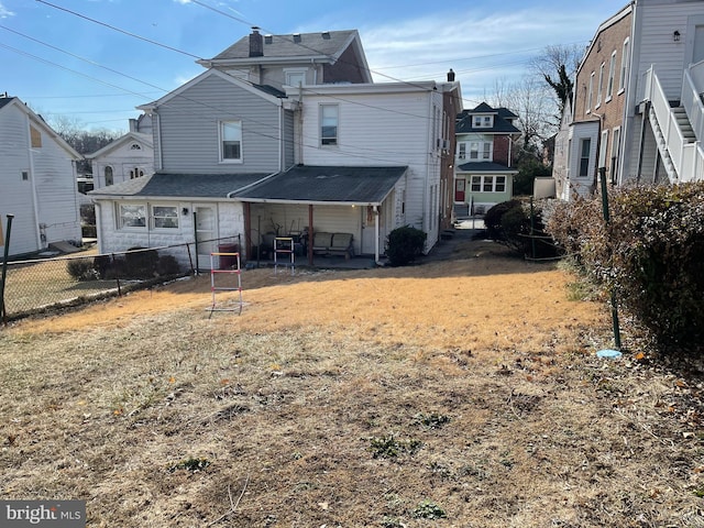 back of property featuring fence, a patio, and a lawn