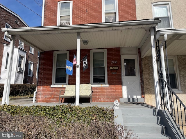 entrance to property with covered porch and brick siding