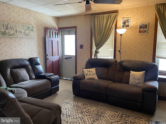 living area featuring wallpapered walls, carpet, and ceiling fan