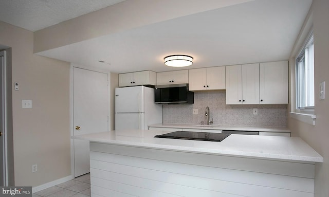 kitchen with light tile patterned flooring, a sink, white cabinetry, freestanding refrigerator, and decorative backsplash