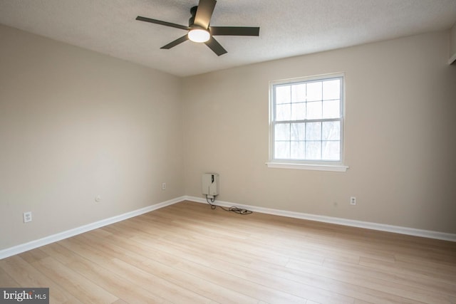 spare room featuring light wood-type flooring, baseboards, and a textured ceiling