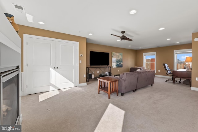 living room featuring a high end fireplace, recessed lighting, visible vents, and light carpet