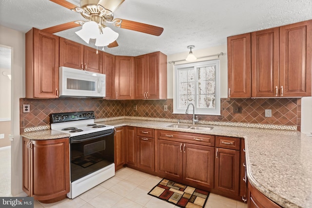 kitchen with electric range oven, white microwave, brown cabinetry, and a sink