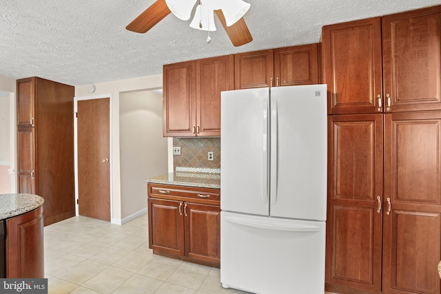 kitchen with light stone countertops, tasteful backsplash, light tile patterned floors, and freestanding refrigerator