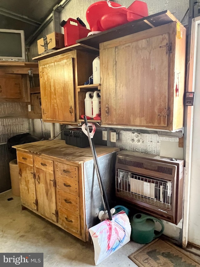 kitchen featuring unfinished concrete flooring, brown cabinets, and heating unit