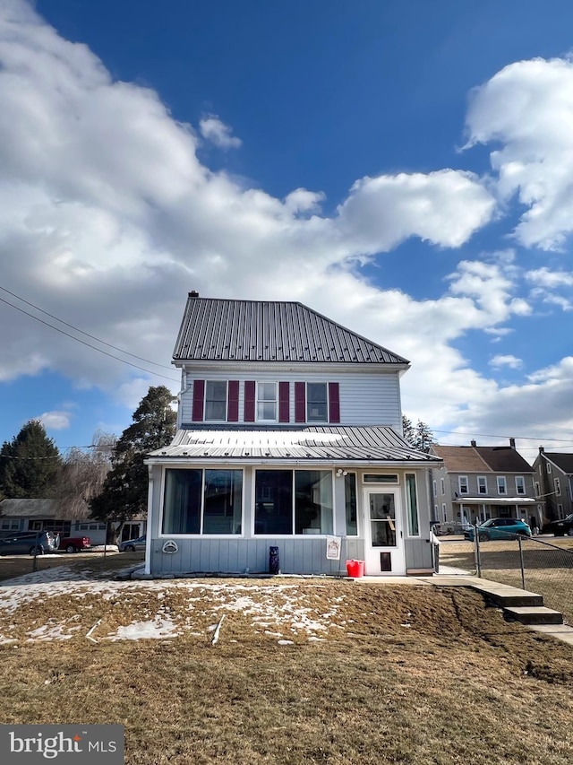 rear view of house featuring metal roof and a yard