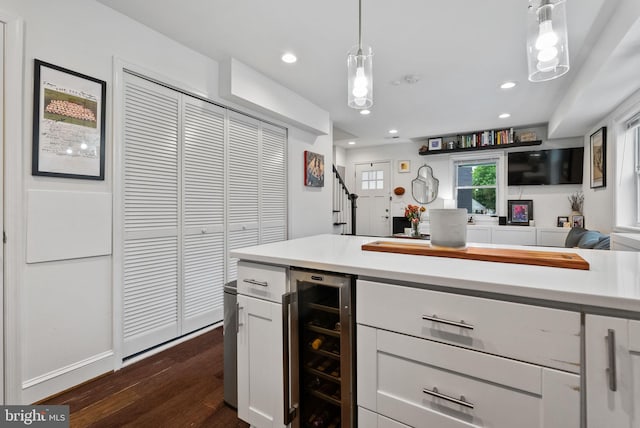 kitchen with wine cooler, dark wood finished floors, light countertops, hanging light fixtures, and white cabinetry