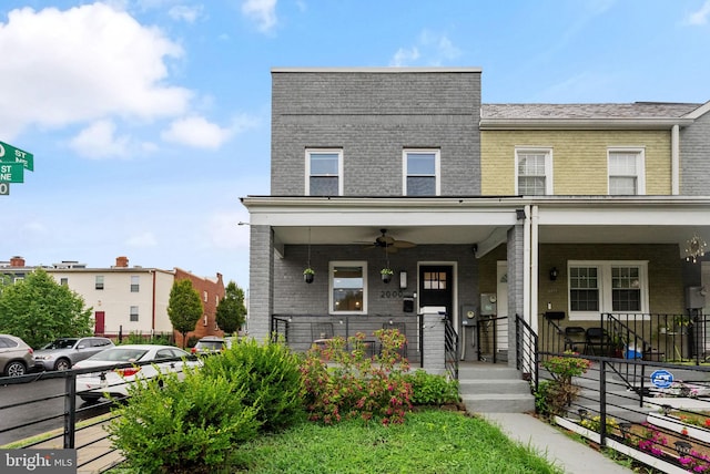 multi unit property with covered porch, ceiling fan, and brick siding