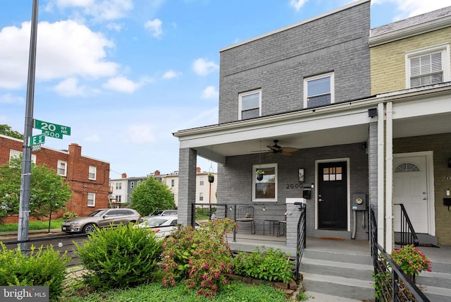 townhome / multi-family property with brick siding, a porch, and a ceiling fan