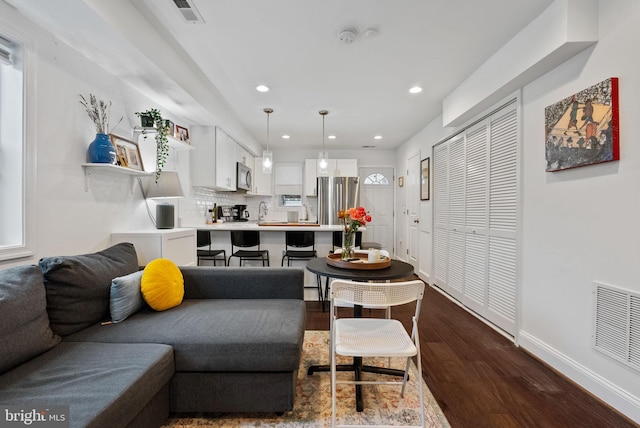 living area featuring baseboards, visible vents, wood finished floors, and recessed lighting