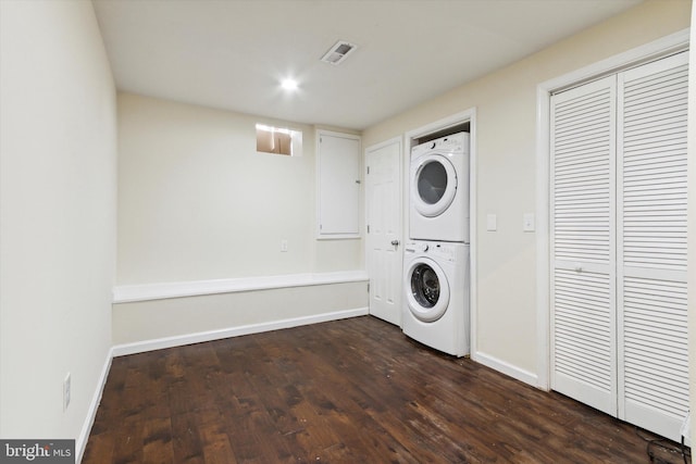 laundry area featuring laundry area, baseboards, visible vents, stacked washer and clothes dryer, and dark wood-type flooring