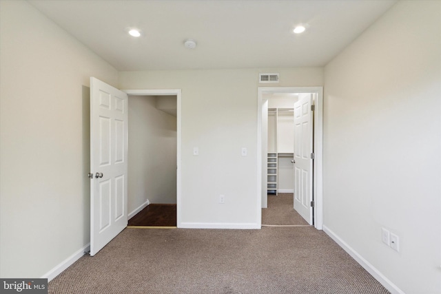 unfurnished bedroom featuring a spacious closet, carpet flooring, and baseboards