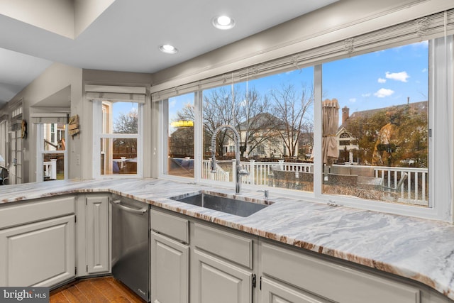 kitchen featuring light stone counters, recessed lighting, a sink, wood finished floors, and dishwasher