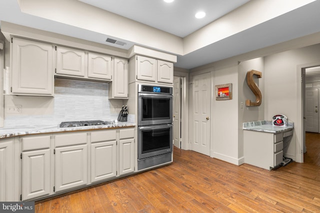 kitchen featuring visible vents, backsplash, appliances with stainless steel finishes, white cabinets, and wood finished floors