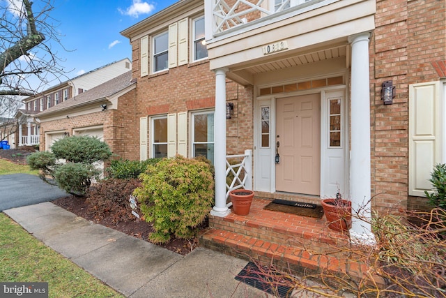 view of exterior entry featuring a garage and brick siding