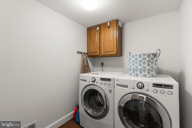 clothes washing area featuring dark wood-style flooring, visible vents, baseboards, cabinet space, and washing machine and clothes dryer