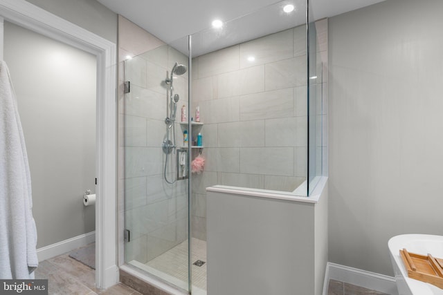 full bath with a freestanding tub, baseboards, and tiled shower