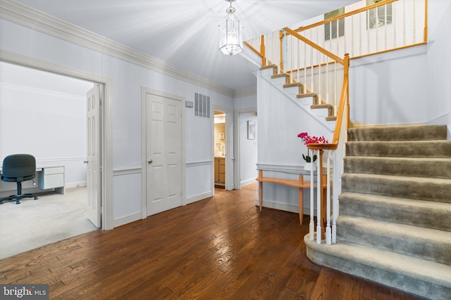 stairway featuring hardwood / wood-style flooring, a notable chandelier, visible vents, baseboards, and crown molding