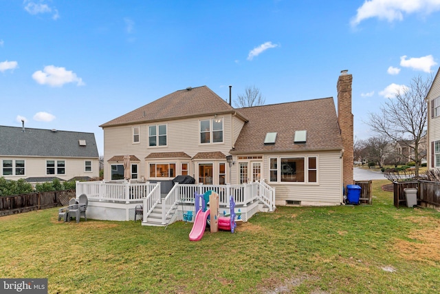 rear view of property with a lawn, a chimney, roof with shingles, fence, and a wooden deck