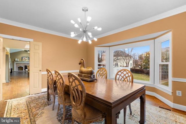 dining space with crown molding, light wood finished floors, visible vents, and a notable chandelier