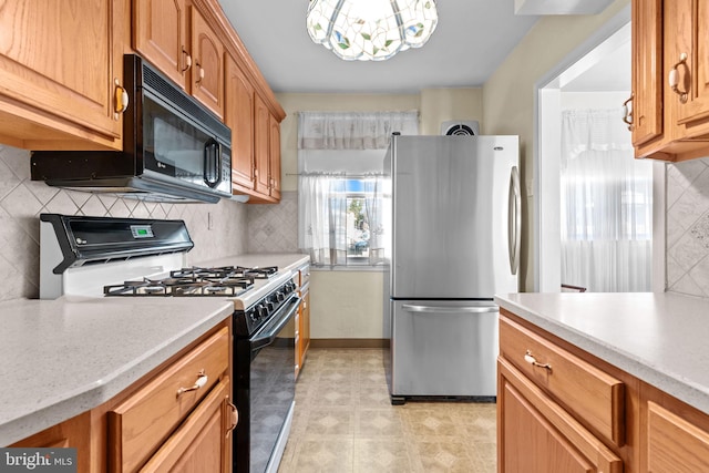 kitchen with black microwave, light countertops, freestanding refrigerator, and range with gas stovetop