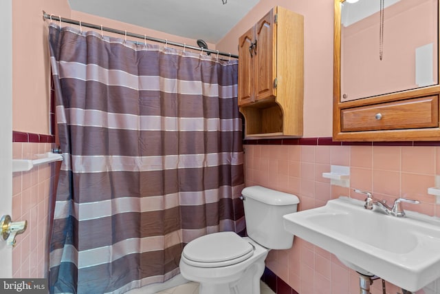 full bath with wainscoting, a sink, toilet, and tile walls