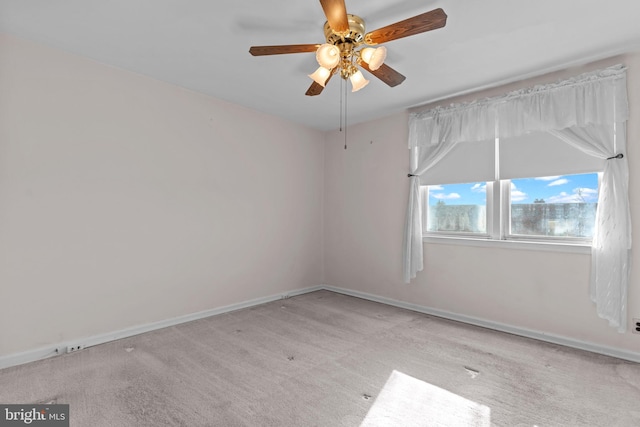 carpeted spare room with a ceiling fan and baseboards