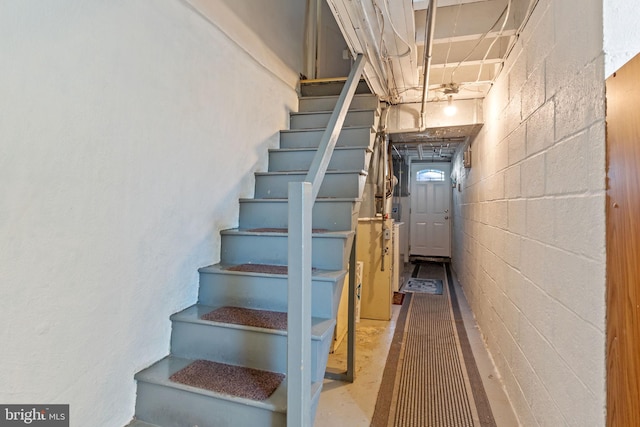 stairs with concrete flooring and concrete block wall