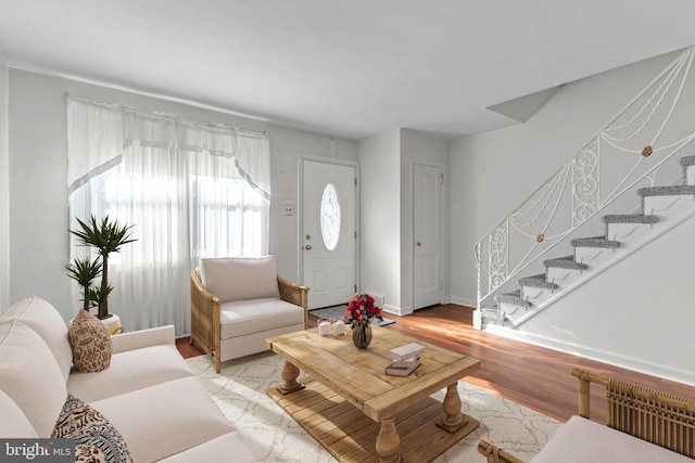 living area with light wood-style floors, radiator, baseboards, and stairs