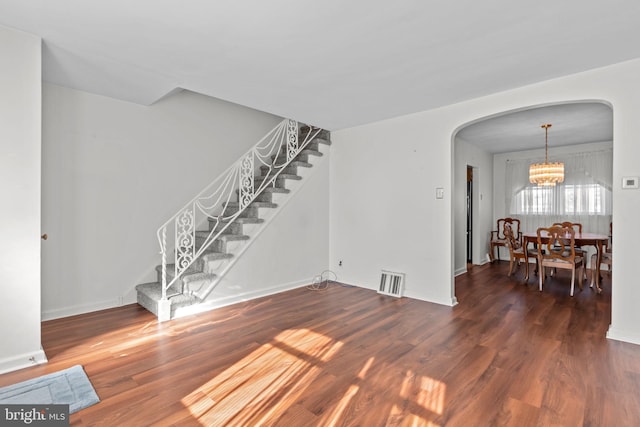 interior space with arched walkways, visible vents, stairway, an inviting chandelier, and wood finished floors