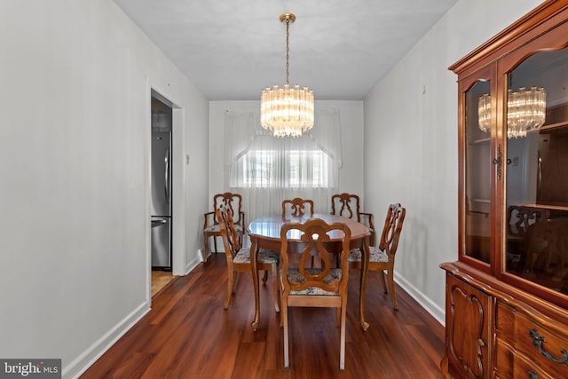 dining room featuring dark wood-style floors, a chandelier, and baseboards