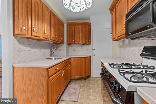 kitchen featuring black microwave, light countertops, white gas range, and a sink