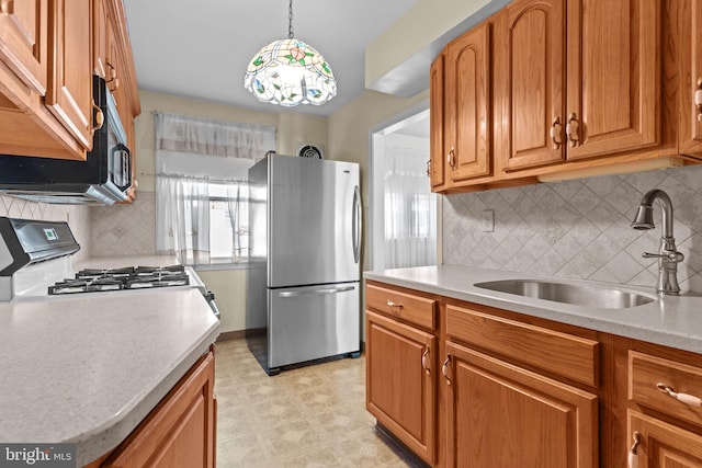 kitchen featuring light countertops, range with gas cooktop, a sink, and freestanding refrigerator