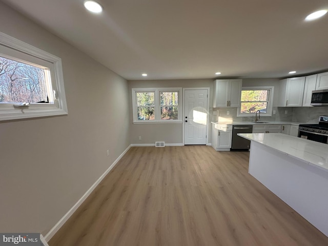 kitchen featuring baseboards, visible vents, decorative backsplash, appliances with stainless steel finishes, and light wood-type flooring